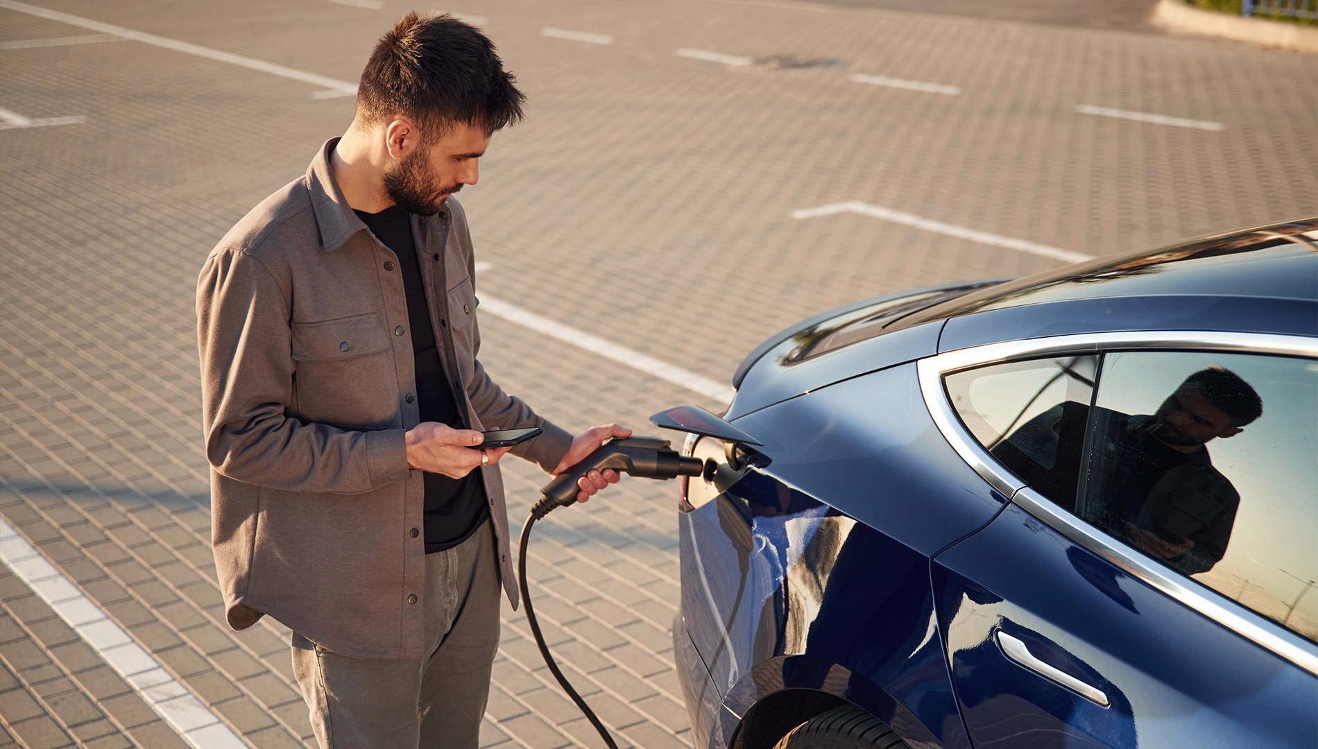 mężczyzna ładuje samochód elektryczny