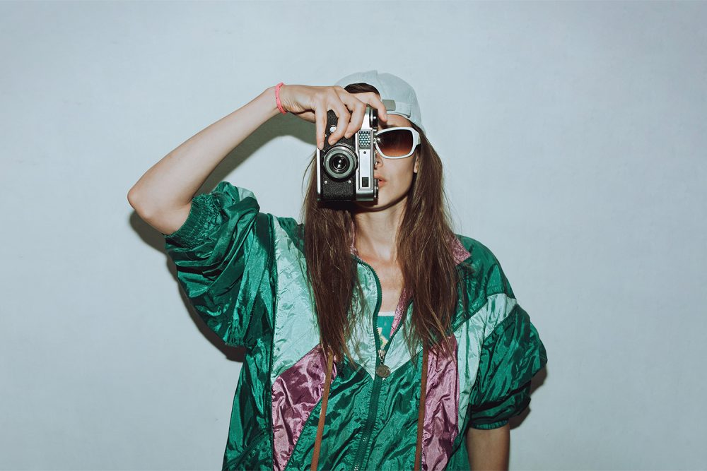 Bazar rozmaitości w M1 Marki. Kobieta w vintage ubraniach robiąca zdjęcie starym aparatem.