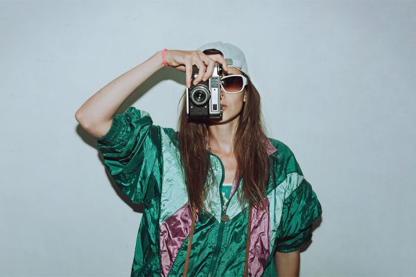 Bazar rozmaitości w M1 Marki. Kobieta w vintage ubraniach robiąca zdjęcie starym aparatem.