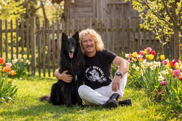 Dni działkowca w M1 Marki. Mężczyzna z psem siedzący na trawie w ogrodzie.