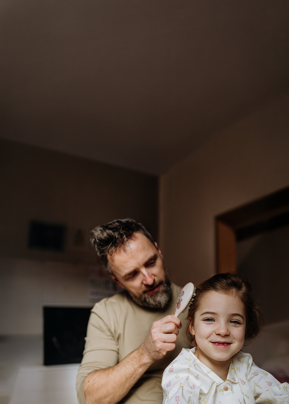 Kampania wizerunkowa w M1 Marki - Bliżej niż myślisz - Tu poznali się moi rodzice. Obraz przedstawiający uśmiechniętego ojca robiącego fryzurę swojemu dziecku